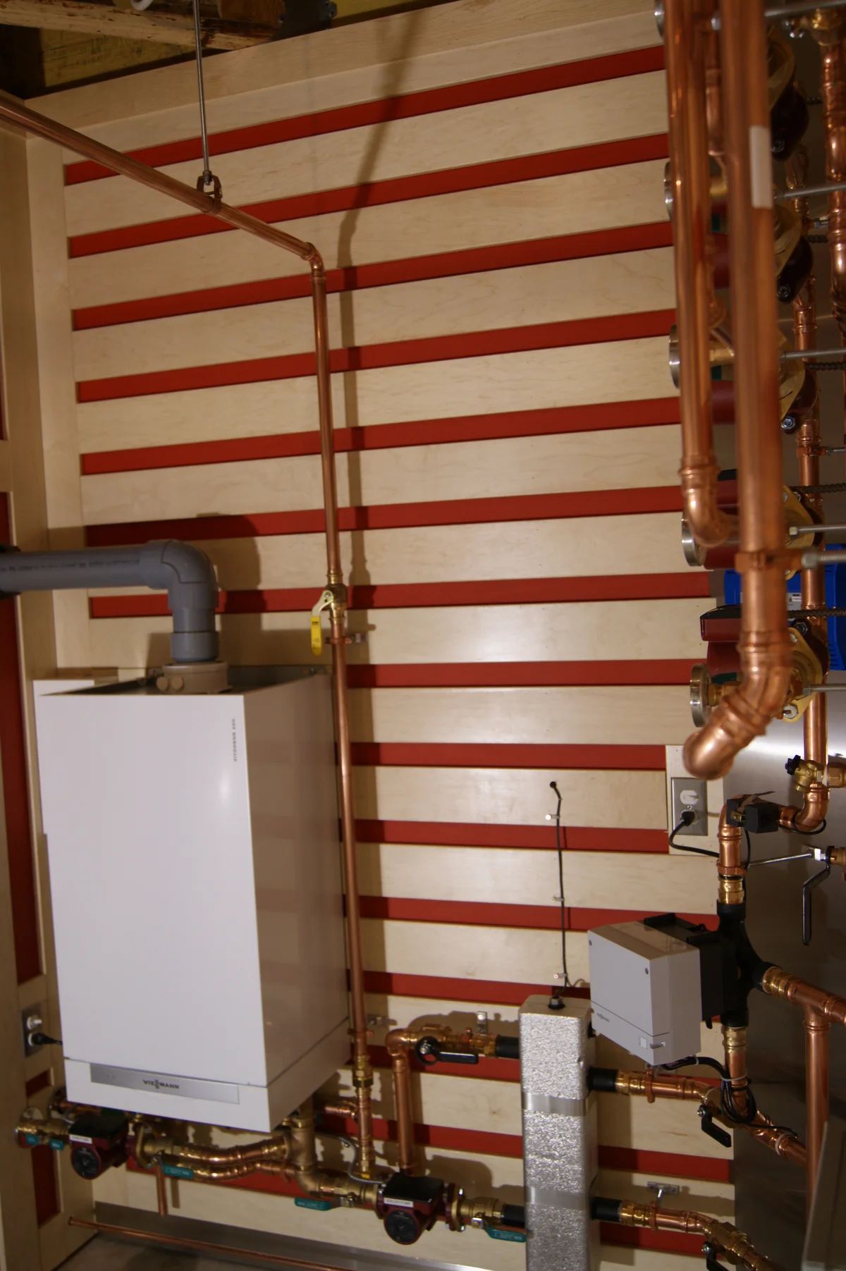 An installed Viessmann Vitodens 200 wall-mounted condensing boiler with copper heating pipes and circulation pumps.